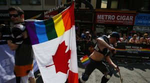 A man holds a rainbow colored Canadian flag attached to a hockey stick during the "WorldPride" gay pride Parade in Toronto