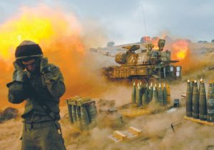 An Israeli soldier stands near a mobile artillery unit as it fires a shell into southern Lebanon