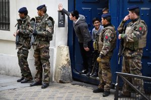 Students peering out from a doorway as armed soldiers patrol outside their school in the Jewish quarter of the Marais district in Paris, Jan. 13, 2015