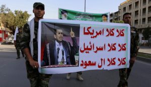 Members of Hashid Shaabi hold a banner of Abdul-Malik al-Houthi during a demonstration to show support for Yemen's Shiite Houthis and in protest of an air campaign in Yemen by a Saudi-led coalition, in Baghdad, March 31, 2015