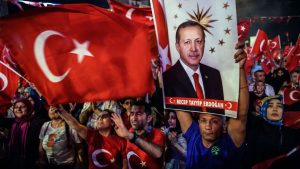 Pro-Erdogan supporters hold Turkish national flags and a portrait of Turkish President Recep Tayyip Erdogan during a rally against the military coup on Taksim square in Istanbul on July 23, 2016.