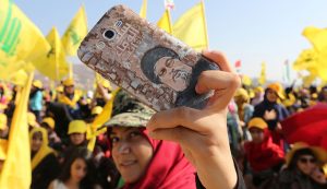 A Hezbollah supporter shows off a picture of Lebanon's Hezbollah leader Sayyed Hassan Nasrallah on her phone during a rally marking the 10th anniversary of the end of Hezbollah's 2006 war with Israel