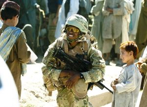 A Royal Marine of 40 Commando (40 Cdo) talks with local children during a foot patrol in Sangin, Afghanistan.