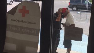 This photo was taken after the Red Cross told the police captain he could not pray inside the shelter. The man he is praying with lost his home in the flood