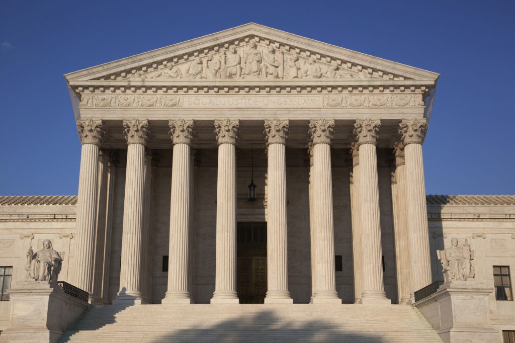 United States Supreme Court Building in Washington, DC, in golden light of late afternoon, against a clear blue sky